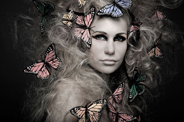 زن جوان زیبا با پروانه در موهای فرفری بزرگ بر روی سیاه و سفید