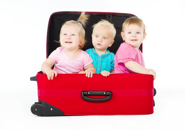 گروهی از سه کودک در داخل چمدان قرمز بزرگ بر روی زمینه سفید نشسته اند