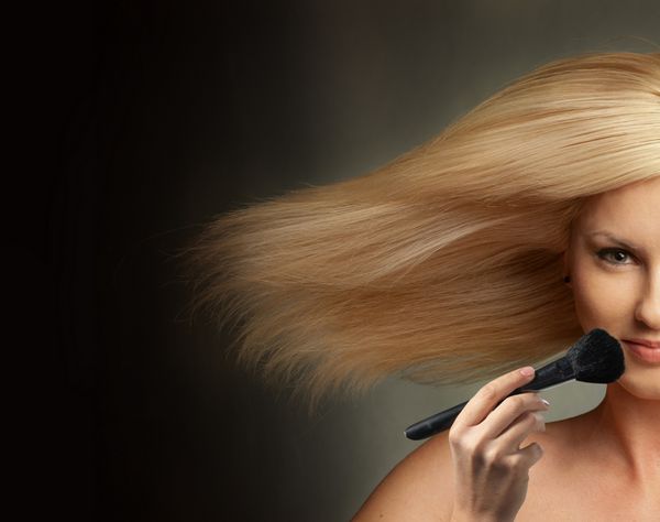 زن با دمیدن مو و با آرایش برس نزدیک صورت