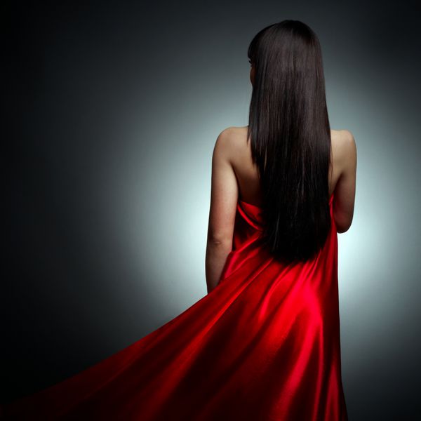 دختر زیبا در لباس قرمز پشت در پس زمینه سیاه و سفید