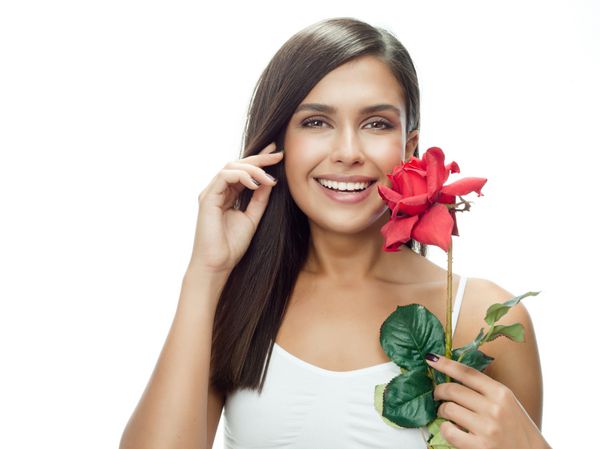 پرتره زن زیبا لبخند زن قهوه ای جدا شده در استودیو سفید با گل رز قرمز به دنبال دوربین
