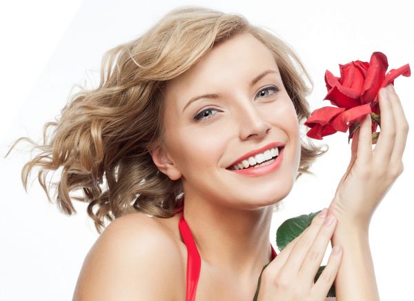 عکسی از زن زیبا لبخند زن قهوه ای جدا شده در استودیو سفید با گل رز قرمز