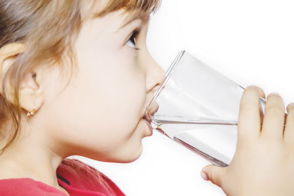 کودک دستش را به یک لیوان آب می زند تمرکز انتخابی