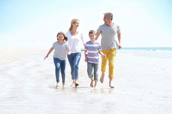 خانواده شاد از چهار راه رفتن در ساحل شنی