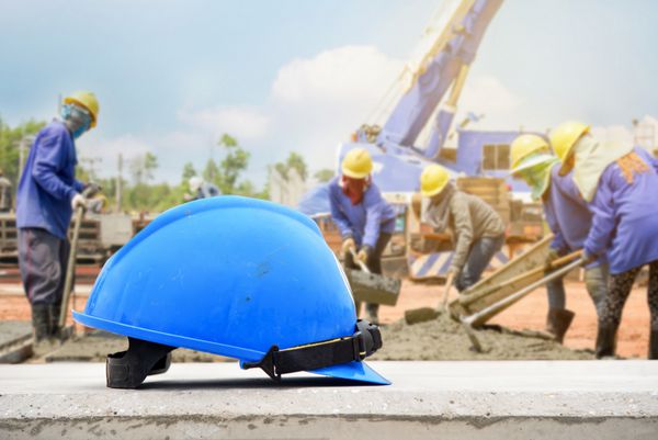 کلاه ایمنی در محل ساخت و ساز و پس زمینه کارگران ساختمانی