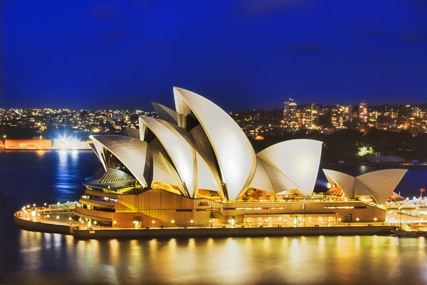 سیدنی استرالیا 21 فوریه 2016 ساختمان سینمایی اپرای سیدنی با روشنایی روشن از پل هاربر سیدنی در غروب خورشید دیده می شود