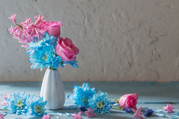 گل های آبی و صورتی در گلدان در پس زمینه گرانج سفید