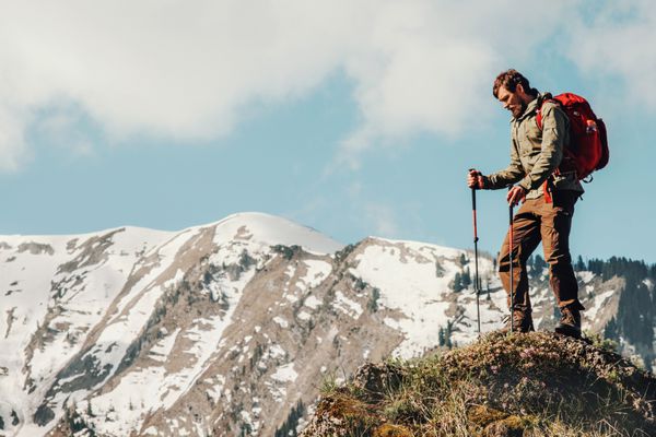 مسافر مرد پیاده روی با کوله پشتی سفر مفهوم سفر تعطیلات تعطیلات تابستان در فضای باز کوه های برفی در پس زمینه