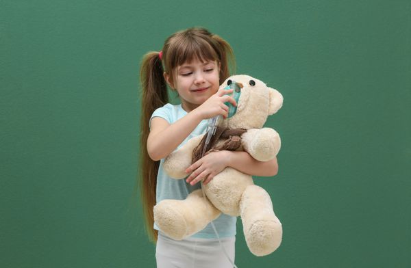 دختر کوچک ناز برگزاری نبولایزر و خرس اسباب بازی در پس زمینه رنگی مفهوم آلرژی