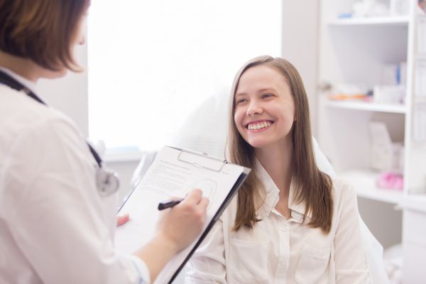 دکتر خانم تشخیص بیمار زن را با لبخند و یادداشت برداری می کند