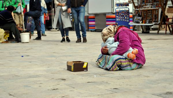 زن بی خانمان شرور با کودک در دستانش گدایی برای پول در خیابان است؛ مردم و مفهوم فقر