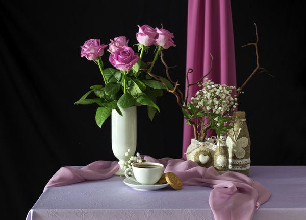 زندگی با گل رز صورتی و قهوه روی میز نزدیک است