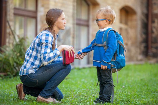 زن و پسر با کوله پشتی در خارج از منزل مدرسه بازگشت به مدرسه مامان به پسر کوچکش توضیح داد روز اول پاییز والدین و دانش آموز مدارس ابتدایی