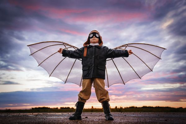 پسر با بال در غروب آفتاب خود را یک خلبان و رویاهای پرواز می کند