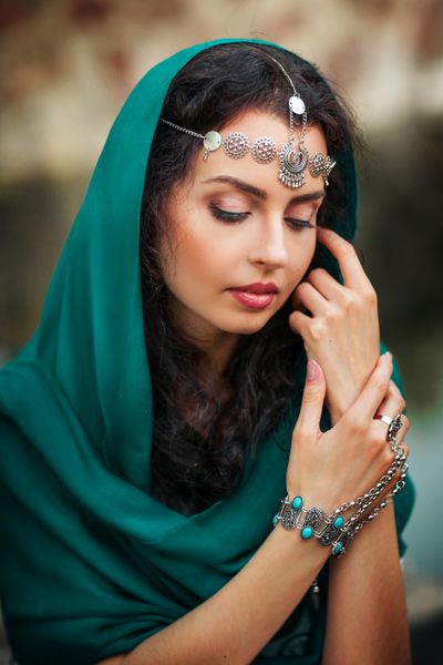 دختر زیبا در روسری و لوازم جانبی هند نشسته نزدیک دیوار سنگ و رویای زن بسیار زیبا به دنبال فضای باز
