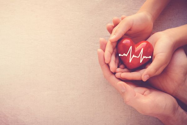 بزرگسالان و کودکانی که دارای قلب قرمز با کارتوگراف مراقبت های بهداشتی عشق و مفهوم بیمه خانواده روز قلب روز هستند