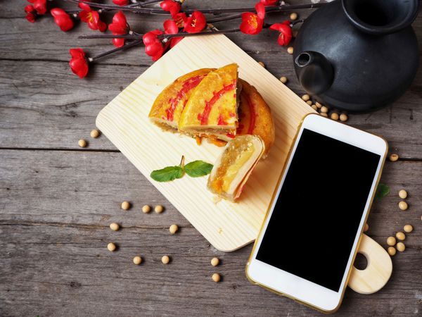کیک شیرینی چینی با ظرف چای و تلفن هوشمند
