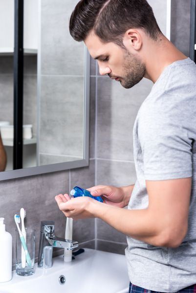 مرد خوش تیپ لوسیون تراشیدن در دست در حمام
