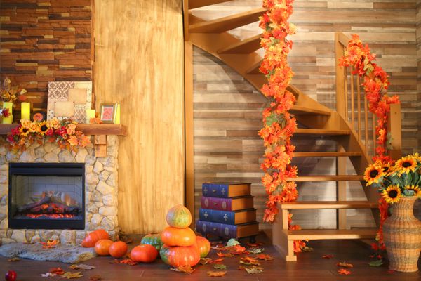 داخلی اتاق با یک شومینه و یک راه پله در سبک پاییز با برگ آفتابگردان و کدو تنبل