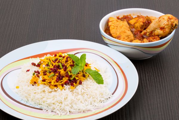 برنج پلوف به عنوان زرشک پولو شناخته شده است که یک ظرف ایرانی ایرانی با زعفران و ادویه پیتزا با گوشت مرغ طعم دار در سس گوجه فرنگی روی میز چوبی
