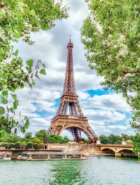 دید کلاسیک در برج ایفل از طریق شاخ و برگ شاخ و برگ سبز بر روی رودخانه سن در پاریس زیبا تابستان تابستان جهت عمودی برج ایفل معروف ترین مقصد سفر در اروپا است