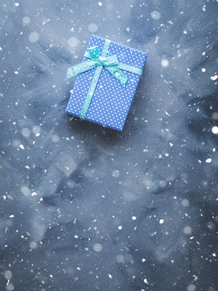 جعبه هدیه تخت با لکه های برف در پس زمینه آبی مفهوم تعطیلات تعطیلات