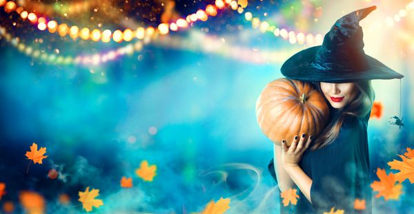 جادوگر هالووین با کدو تنبل و چراغ سحر و جادو در یک جنگل تاریک زن زیبا زن شگفت زده در جادوگران کلاه و صحنه و لباس کدو تنبل طراحی هنری حزب هالووین