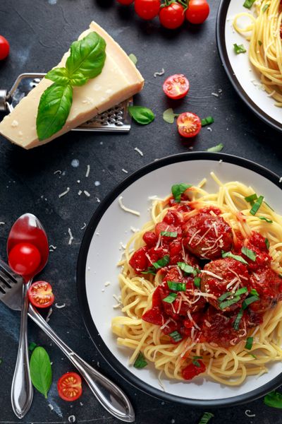 کیک پاستا اسپاگتی با سس گوجه فرنگی ریحان پنیر پارمسان گیاهان در پس زمینه تیره