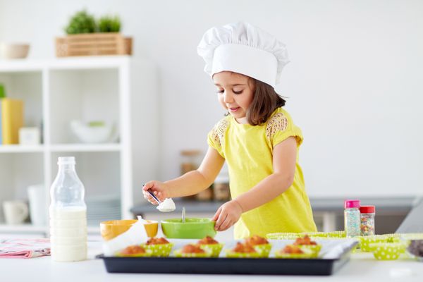 خانواده پخت و پز پخت و مفهوم مردم دختر کوچک در سرآشپزها toque ساخت خمیر برای کلوچه یا کیک در آشپزخانه خانه