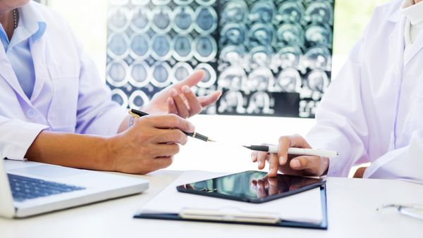 دو پزشک در حال تجزیه و تحلیل اسکن یا اشعه ایکس فیلم یا توضیح می دهد CT اسکن همراه با روش جدی تفکر تفکر با نتایج درمان بیمار در مغز به انحراف در فیلم