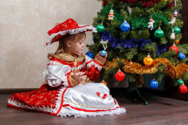 دخترک در کارناوال لباس نگه داشتن توپ کریسمس