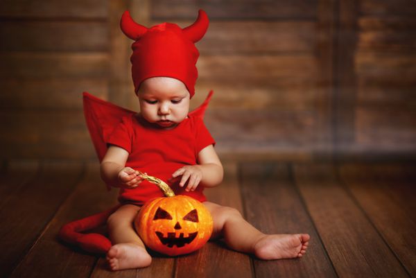 بچه های بامزه در لباس هالووین شیطان با کدو تنبل