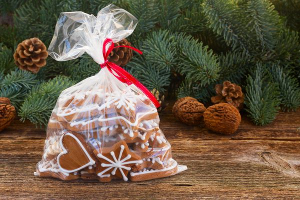 کوکی شیرینی زنجفیلی کریسمس در کیسه شفاف با درخت شاه بلوط و مخروط