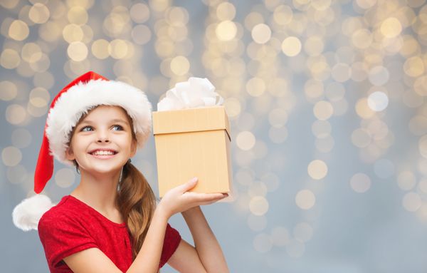 دختر لبخند زدن در کلاه سانتا با جعبه هدیه کریسمس
