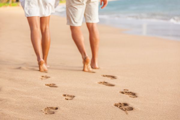 زن و شوهر ساحل آرامش بخش در غروب خورشید راه رفتن پابرهنه تمرکز بر ردیابی در شن و ماسه طلایی نزدیک شدن پاها تعطیلات تعطیلات ساحلی عاشقانه جوانان از پشت پیاده روی به سوی خوشبختی
