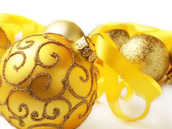 توپ های کریسمس طلایی با روبان در زمینه سفید عمق کم عمق میدان