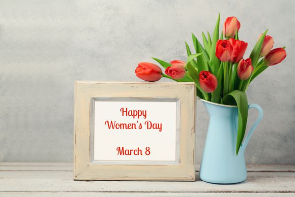 مفهوم روز زنان 8 مارس با گل لاله و قاب عکس روی میز چوبی