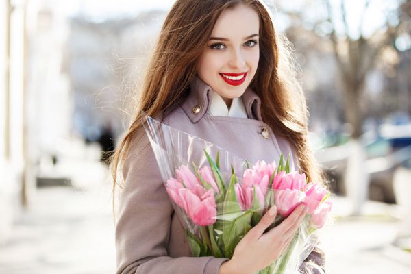 دختر خوشگل لبخند با گل گل لاله در خارج از منزل