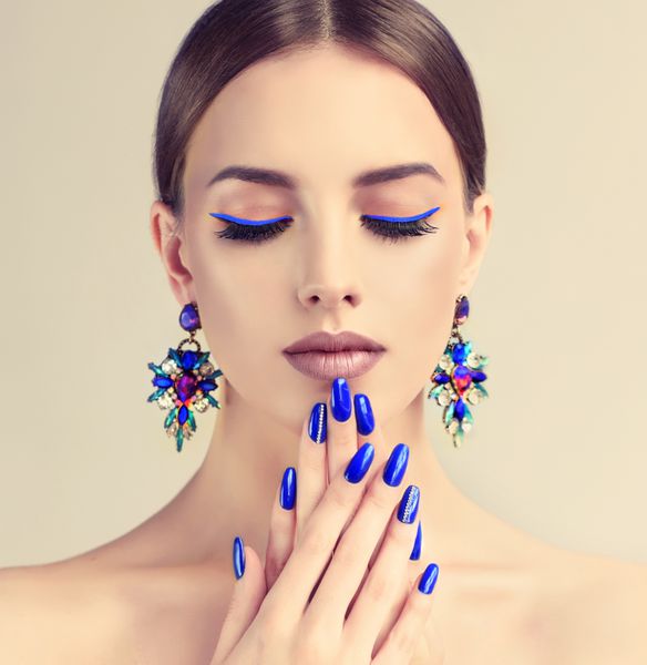 دختر مدل زیبا با مانیکور آبی روی ناخن آرایش مد و آرایشی جواهرات گوشواره های بزرگ