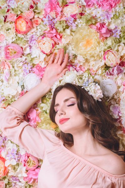 دختر زیبا با گل گلدان در سر بر روی دیوار از گل