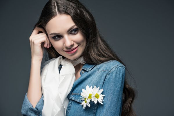 لبخند زدن دختر در روسری و پیراهن جین با گل جدا شده در خاکستری