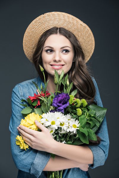دختر شاد زیبا در کلاه نی که برگ های گل برای روز جهانی بین المللی زنانه است در خاکستری جدا شده است