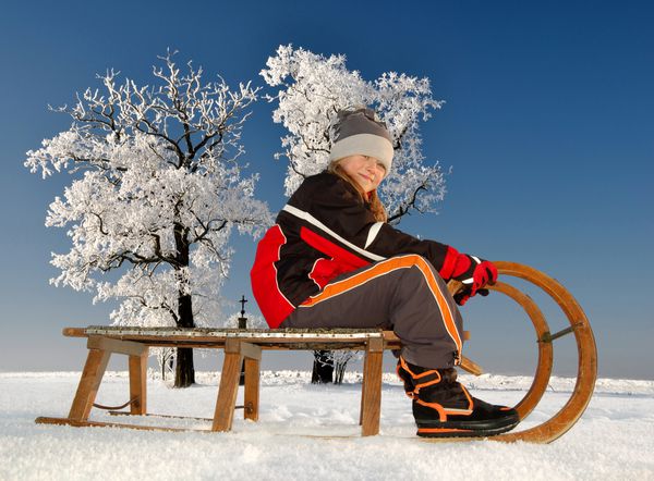 دختر در یک سورتمه در چشم انداز زمستانی