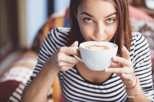 زن جوان نوشیدن قهوه در کافه شهری
