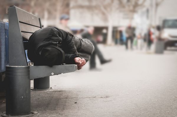 مرد فقیر بی خانمان و یا پناهنده در خواب بر روی نیمکت چوبی در خیابان های شهری در شهر مفهوم مستند اجتماعی انتخابی تمرکز