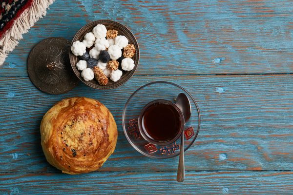 گوگال و شیشه چای سیاه با غذای سنتی سنتی در کاسه مسی در میز چوبی روستایی شیرینی تعطیلات نروژ آذربایجان