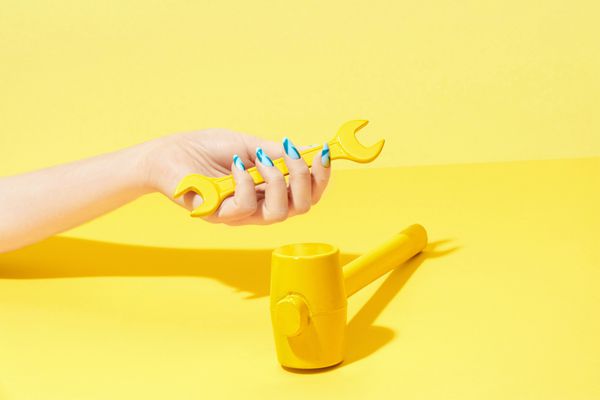 طراحی ناخن دست با ناخن های رنگارنگ در پس زمینه زرد نزدیک دست زنانه با زیبایی مانیکور هندسی روشن و چکش رنگی در پس زمینه زرد تصویر با کیفیت بالا