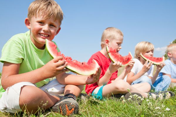 بچه ها خوردن هندوانه قرمز در پس زمینه آبی رنگ