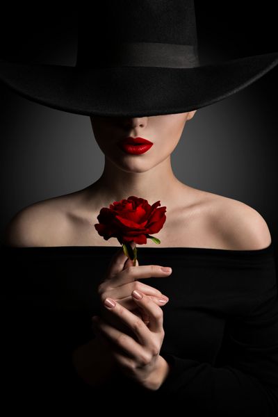 زن در کلاه برگ گل رز در دست مد مدل زیبایی پرتره لب قرمز و کلاه سیاه و سفید گسترده