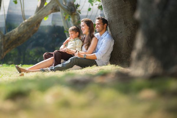 خانواده شاد با مرد زن و کودک تکیه بر درخت در پارک شهر فضای کپی کنید